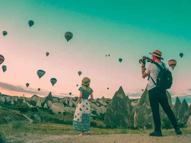 Travellers watching hot-air balloons at sunrise